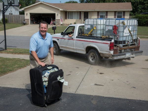 man-smiling-with-suitcase-of-money-as-pickup-drives-away.jpeg